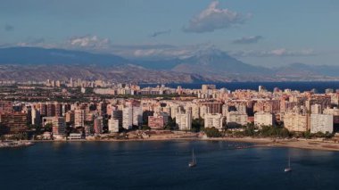 Alicante şehrinin panoramik manzarası. Açık bir gökyüzü altında, konut binaları, sahil şeridi ve uzak dağlar. Yüksek kalite 4k görüntü