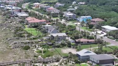 Gündüz vakti ağaçlar ve beyaz binalarla çevrili bir sahilin yüksek açılı görüntüsü.