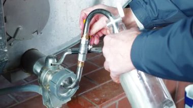 Süt çiftliğindeki bir adam süt deposundaki musluktan taze ineklere süt döker. Yüksek kalite 4k görüntü