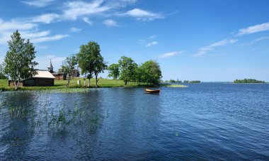Kizhi, Karelia, Rusya 'daki açık hava müzesinin tarihi binalarıyla birlikte Onega Gölü' ndeki tekne, Haziran 2019