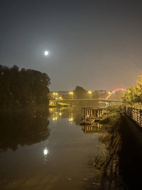 Tartu, Tartumaa, Estonya, Eylül 2023 'te Emajgi nehri üzerinde sisli bir dolunay gecesi.