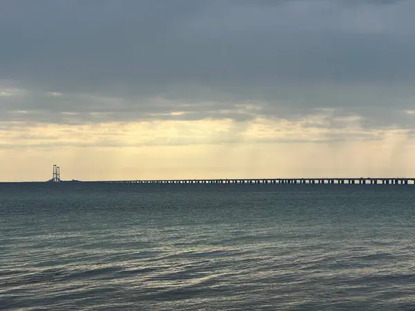 Storeblt Boğazı üzerindeki Büyük Kemer Köprüsü fırtınalı gündoğumu gökyüzünün altında Nyborg, Güney Danimarka, Haziran 2023