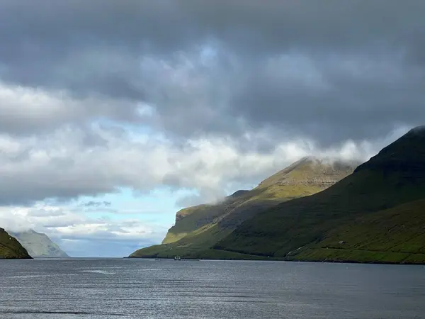 Srvgsfjrur fiyortu, Atlantik Okyanusu ve Srvgur, Vgar, Faroe Adaları 'ndaki dağların üzerindeki bulutlar, Ağustos 2023
