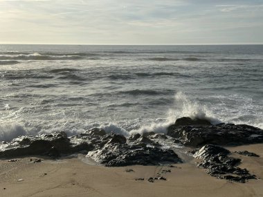 Atlantik Okyanusu dalgaları Vila do Conde, Porto, Portekiz yakınlarındaki kaya ve kumsal sahillerinde kırılıyor, Ocak 2024