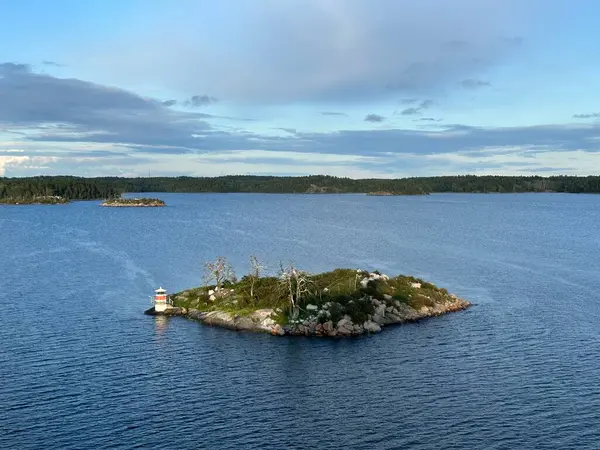Cüce ağaçları ve Stockholm takımadasındaki küçük deniz feneri olan küçük kayalık bir ada, Sterkers kommun, İsveç, Ağustos 2023