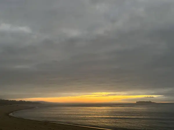 Atlantik Okyanusu üzerinde gün batımı, Praia de Caminha ve Santo Isidro adaları Forte da Insua kalesi, Viana do Castelo, Portekiz, Ocak 2024