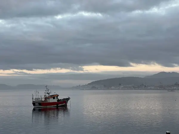 Caminha, Viana do Castelo, Portekiz yakınlarındaki bulutlu bir gökyüzünün altında, sakin bir nehirde balıkçı teknesi, Minho, Ocak 2024