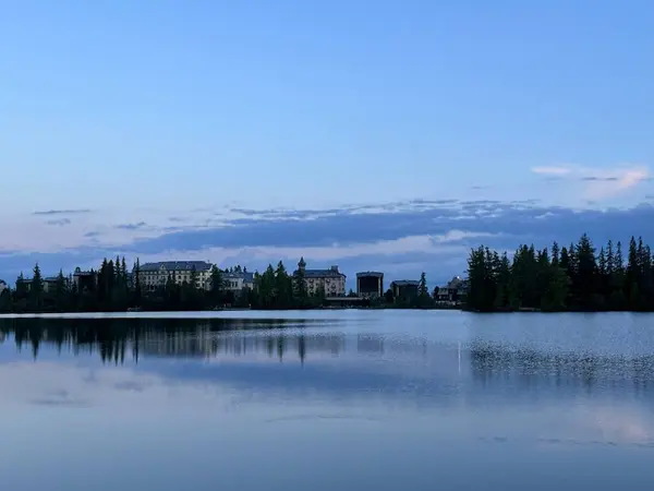 Trbsk pleso Gölü, Trba, Poprad, Preov, Slovakya, Mayıs 2024 'te ağaçların ve Grand Hotel binalarının yansıması.