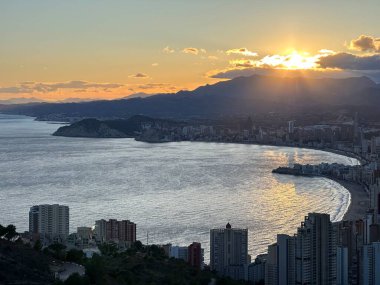 Benidorm şehrinde günbatımı ufuk çizgisi, sahil ve çevre dağlar, Valencia Topluluğu, İspanya, Mart 2024