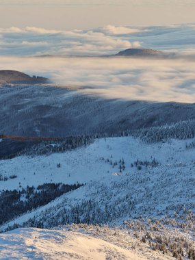 Karkonosze Dağları 'nın kış manzarası gün doğumunda Sniezka' nın tepesinden görüldü. Dağ yamaçlarında bulut inversiyonu.