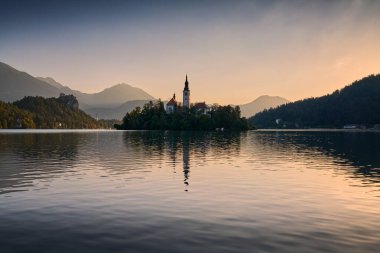Bir sonbahar sabahı gün doğumunda Bled Gölü manzarası. Arka planda Alpler ve Kanlı Kale.