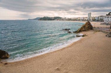 Bulutlu bir günde Playa de Fenals plajı ve deniziyle Lloret de Mar 'ın manzarası. İspanya 'da Costa Brava kıyıları.