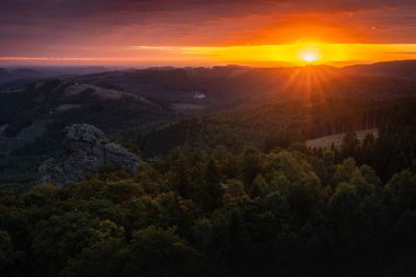Alman Sauerland bölgesinde, ön planda Bruchhausen Steine kayaları olan ateşli bir gündoğumu.