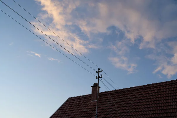 Roof of a house with electrical wires in the evening