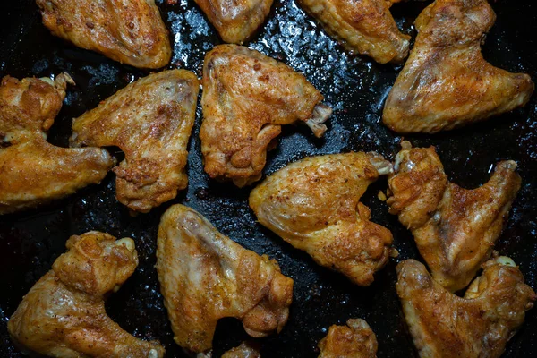 Top view of crispy chicken wings on a black baking sheet