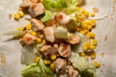 Close up of a delicious wrap with lettuce, corn and fried chicken meat