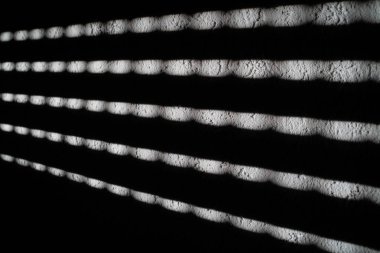 Pencereden süzülen güneş panjurları ve duvarlara çizgiler çiziyor.