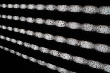 Parlak güneş pencerelerden parlıyor. Panjurlar ve çizgiler duvara vuruyor.