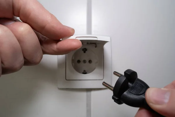 Male hand inserts a power plug into the socket