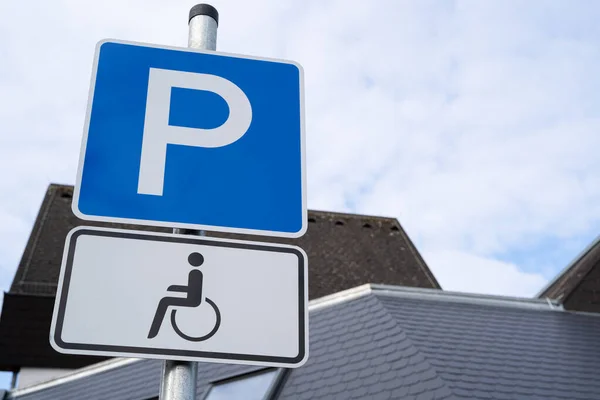 Blue and white parking sign with wheelchair for drivers with disabilities