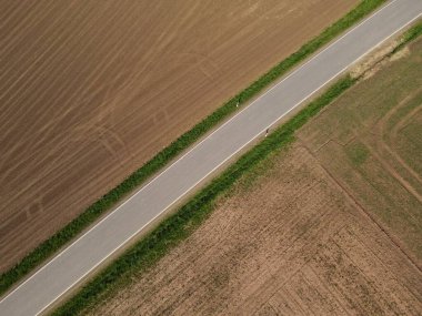 Toprakta toprak bulunan tarlalar arasında asfalt bir yolun havadan görünüşü 