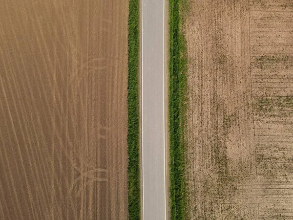 田舎の土壌を有する耕作農地との間の道路の上からの眺め — ストック写真