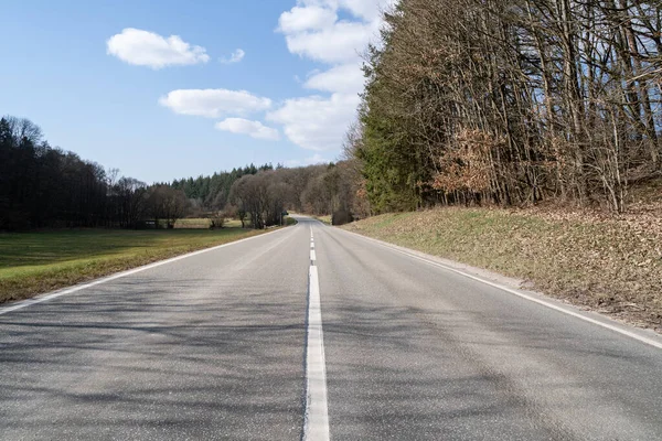 stock image Rural road with leafless trees on the sides and a blue sunny sky in spring