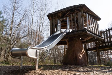 Oyun parkında çocuklar için kaydıraklı tahta oyun evi.