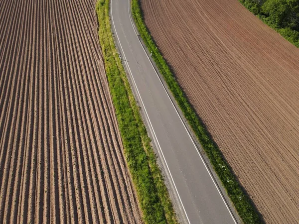 景観における耕作農地と耕作農地との間のアスファルト道路の空中ビュー — ストック写真
