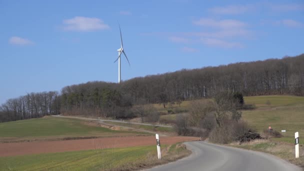 春天的风景 有柏油路 无叶树木和蓝天的风力涡轮机 — 图库视频影像