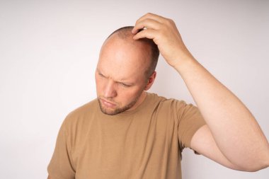 Kahverengi tişörtlü genç adam başını kaşıyarak daha iyi bir çözüm düşünüyor.