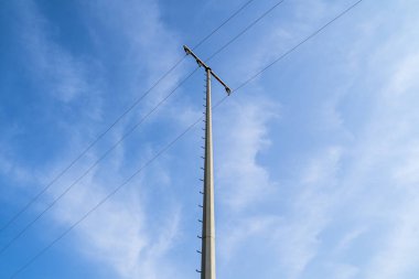 Mavi güneşli gökyüzünde yüksek voltajlı elektrik hatlarına sahip pilon.