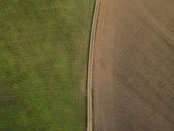 从草地和犁地之间的土路的上方看 — 图库照片