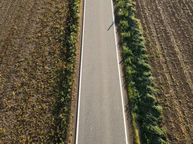 Kahverengi tarım arazileri ile kırsal kesimdeki toprak arasındaki bir yolun havadan görünüşü