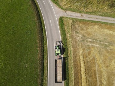 Manzarada yol boyunca bir karavanla bir traktörün üstünden görünüm