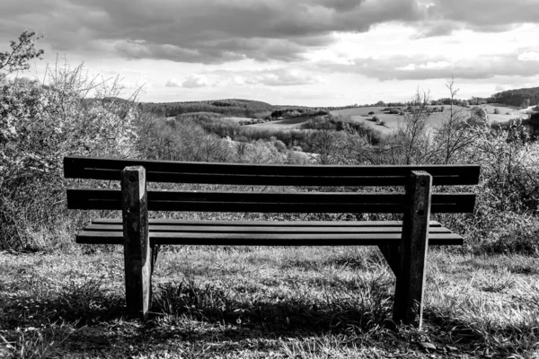Bench on the hill with a view of the landscape in black and white