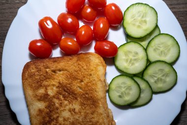 Kızarmış yumurtalı tost, domates ve salatalıkla kahvaltı.