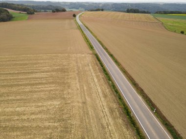 Kırsal kesimdeki çiftlik arazileri arasında uzun bir yolun havadan görünüşü 