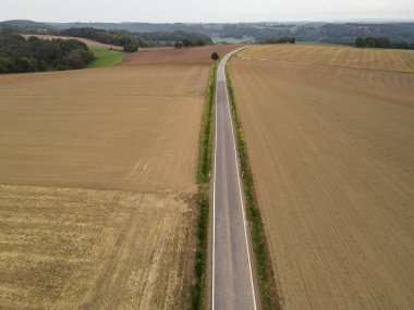 Kırsal kesimdeki çiftlik arazileri arasında uzun bir yolun havadan görünüşü 