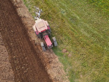 Kırmızı traktörün havadan görünüşü tarlayı sürüyor. 