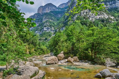 Landscape of the Aisclo Canyon valley, with high rocky mountains, green forests, and rivers in Ordesa National Park, Huesca, Aragon, Spain.