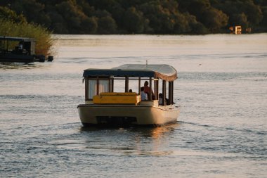 Afrika 'nın Zimbabve kentindeki Zambezi Nehri' nde gün batımı gezisinin tadını çıkaran turistler.