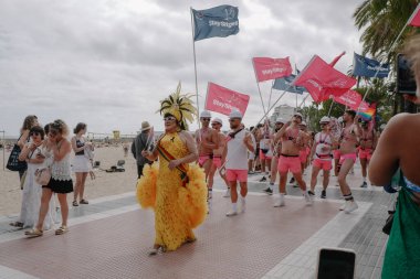 Sitges, İspanya - 8 Haziran 2025: İnsanlar Sitges Onur Yürüyüşü sırasında gökkuşağı bayrakları sallayarak renkli kıyafetler içinde sevinçle yürüyorlar. Kalabalık deniz kenarında aşkı, çeşitliliği ve LGBTQ + gururunu kutluyor.