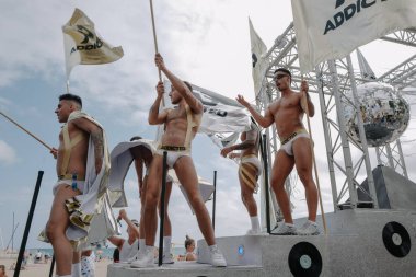 Sitges, İspanya - 8 Haziran 2025: Kalın kostümlü katılımcılar Sitges Onur Yürüyüşü sırasında renkli bir şamandırada dans edip tezahürat yapıyorlar. Festival sahnesi özgürlüğü, çeşitliliği ve LGBTQ + gururu kutluyor.