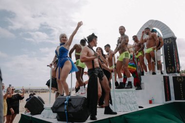 Sitges, İspanya - 8 Haziran 2025: Kalın kostümlü katılımcılar Sitges Onur Yürüyüşü sırasında renkli bir şamandırada dans edip tezahürat yapıyorlar. Festival sahnesi özgürlüğü, çeşitliliği ve LGBTQ + gururu kutluyor.