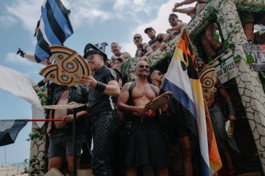 Sitges, İspanya - 8 Haziran 2025: Kalın kostümlü katılımcılar Sitges Onur Yürüyüşü sırasında renkli bir şamandırada dans edip tezahürat yapıyorlar. Festival sahnesi özgürlüğü, çeşitliliği ve LGBTQ + gururu kutluyor.