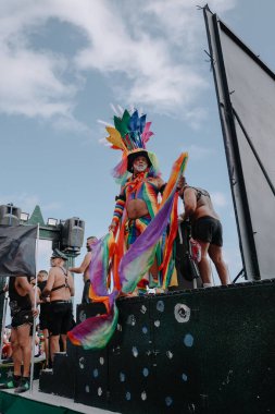 Sitges, İspanya - 8 Haziran 2025: Gökkuşağı kostümü içindeki gri saçlı bir adam, Akdeniz kıyıları tarafından kapsama, özgürlük ve LGBTQ gururunu simgeleyen Sitges Onur Yürüyüşü sırasında şü 'nde neşeyle kutluyor.