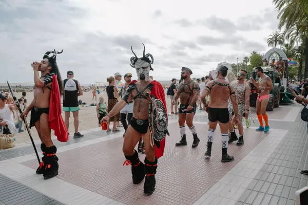 Sitges, İspanya - 8 Haziran 2025: İnsanlar Sitges Onur Yürüyüşü sırasında gökkuşağı bayrakları sallayarak renkli kıyafetler içinde sevinçle yürüyorlar. Kalabalık deniz kenarında aşkı, çeşitliliği ve LGBTQ + gururunu kutluyor.