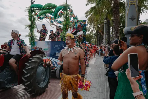 Sitges, İspanya - 8 Haziran 2025: İnsanlar Sitges Onur Yürüyüşü sırasında gökkuşağı bayrakları sallayarak renkli kıyafetler içinde sevinçle yürüyorlar. Kalabalık deniz kenarında aşkı, çeşitliliği ve LGBTQ + gururunu kutluyor.