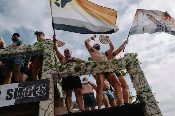 Sitges, İspanya - 8 Haziran 2025: Kalın kostümlü katılımcılar Sitges Onur Yürüyüşü sırasında renkli bir şamandırada dans edip tezahürat yapıyorlar. Festival sahnesi özgürlüğü, çeşitliliği ve LGBTQ + gururu kutluyor.
